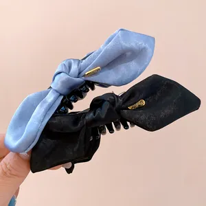 Elegant satin bow hair claw clips in blue and black shown in a detailed close-up