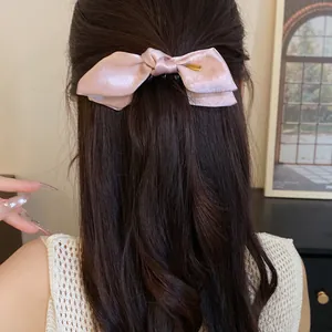 Detail view of a elegant pink satin bow hair clip worn by a model for a chic look.