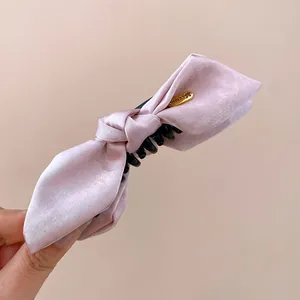Detailed view of the pink satin bow hair claw clip with a elegant gold metal tag