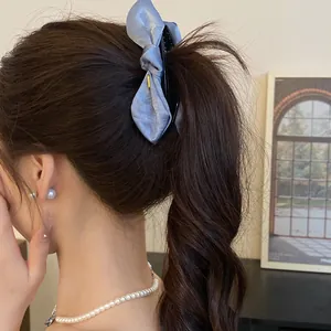 Detail shot of a light blue satin bow hair clip elegantly styled in a ponytail