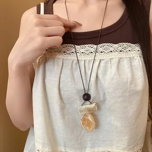 Dettaglio di una collana bohémien vintage in pelle con pendenti geometrici in resina