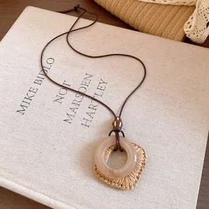 Dettaglio di una collana bohémien con ciondolo quadrato in resina e intrecciato su cordino.