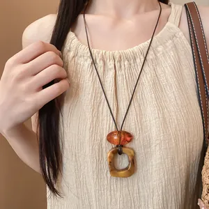 Primo piano di una collana bohémien con pendente in resina e cordino in cuoio su modella