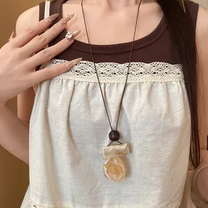 Primo piano di una collana pendente in resina boho retrò con trama marmorizzata su cordino.