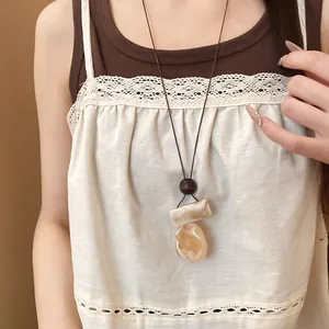 Dettaglio di collana bohemian retrò con ciondolo in resina marmorizzata color crema