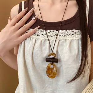 Dettaglio di una collana bohémien con ciondolo in resina su cordoncino in pelle ambrata