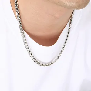 Close-up of a silver stainless steel Cuban link chain necklace on a white t-shirt
