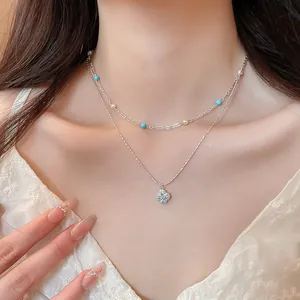Close-up of elegant double-layer necklace with sparkling zircon flower pendant and pearls