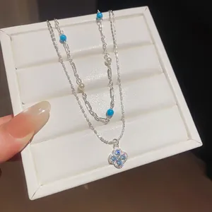 Close-up of silver-plated double-layer necklace with blue zircon clover pendant and pearls