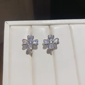 Close-up of sparkling zircon clover flower earrings on white leather jewelry display