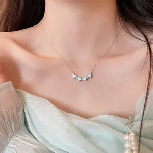 Detailed view of silver heart pendant necklace with light blue stones on a model