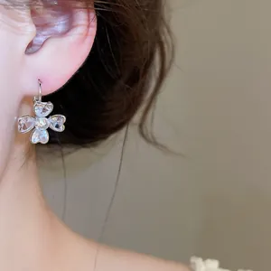 Detailed macro view of silver-toned four-leaf clover earring with sparkling heart zircons
