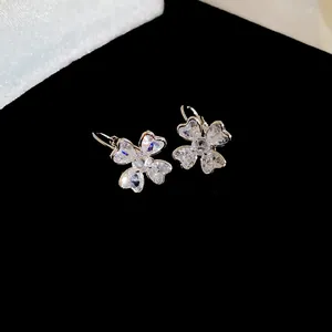 Close-up of silver-tone clover earrings with heart-shaped sparkling cubic zirconia.