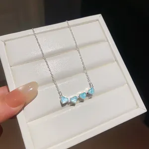 Close-up detail of silver necklace with blue heart-shaped flower pendant on jewelry box