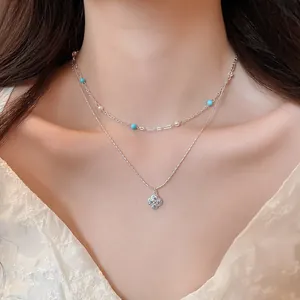 Close-up of an elegant double-layered necklace with zircon flower pendant and pearls