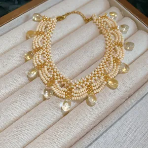 Detail view of a cream beaded choker necklace with gold accents and clear teardrop charms