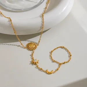 Dettaglio di una catena da mano in acciaio dorato con ciondoli a forma di sole e luna.