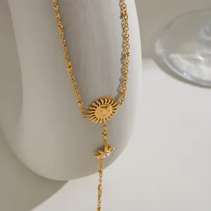 Primo piano di un bracciale da dito sole e luna in acciaio dorato su un supporto bianco.