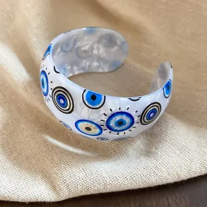 Bracelet jonc élégant en acrylique avec motif œil bleu sur un fond de tissu beige doux