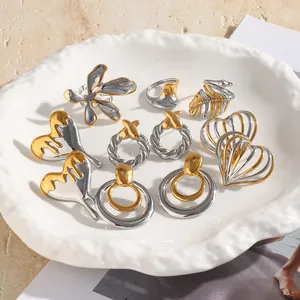Colección de pendientes y anillos bicolores de acero inoxidable en un plato blanco