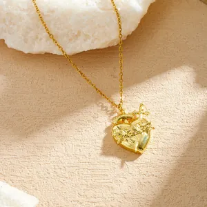 Detail view of a gold-plated Gothic heart pendant with intricate rose and sword engravings.