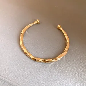 Elegante goudkleurige gedraaide open armband met bolsluiting voor modieuze vrouwen