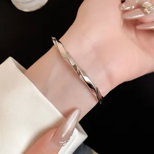 Detailopname van een gepolijste zilverkleurige gedraaide metalen armband om de pols