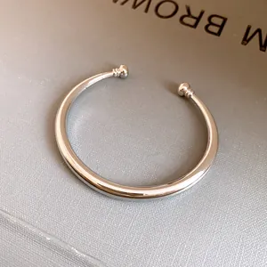 Detailopname van een minimalistische zilver gepolijste metalen open manchetarmband