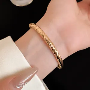 Close-up van een elegante goudkleurige getextureerde open armband met luxe metalen finish