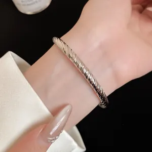 Detailopname van een getextureerde zilveren armband met elegant gravure.