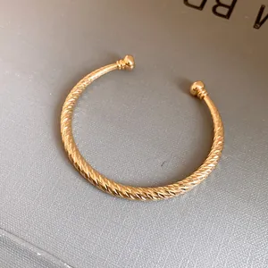 Gedetailleerde macro-opname van een goudkleurige open armband met diamantgeslepen textuur.