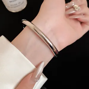 Close-up van een minimalistische zilveren metalen open armband met een glad gepolijste afwerking.