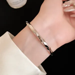 Macrodetail van een minimalistische zilveren gedraaide metalen armband om de pols