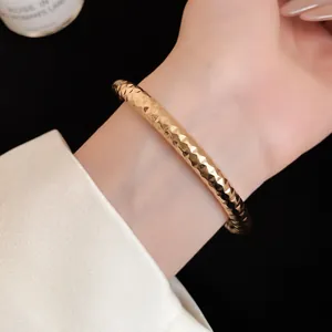 Gedetailleerd overzicht van een goudkleurige gehamerde metalen armband voor dames