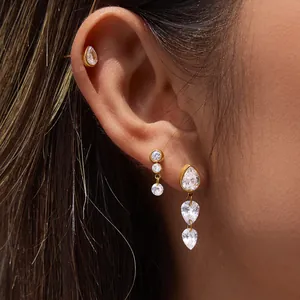 Détail de boucles d'oreilles de luxe en acier titane doré avec des zircons clairs