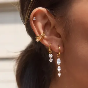 Détail de la manchette d'oreille en acier doré et des boucles d'oreilles en zircon