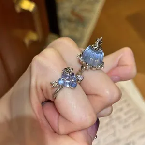 Detail of light blue pudding resin ring and zircon grape cluster ring worn on a hand.