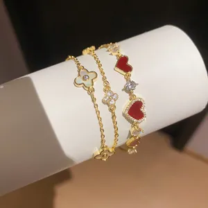 Nahaufnahme von 14k vergoldeten Armbändern mit Zirkonherzen und Muschel-Kleeblatt-Anhängern