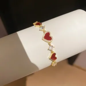 Nahaufnahme eines 14k vergoldeten Armbands mit rotem Herz und funkelnden Zirkoniasteinen