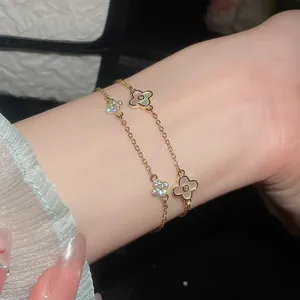 Nahaufnahme goldener Kleeblatt-Armbänder mit funkelnden Zirkonien und Perlmutt-Inlay