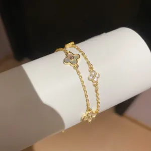 Nahaufnahme eines goldenen Kleeblatt-Armbands mit Perlmutt und Zirkonia-Steinen