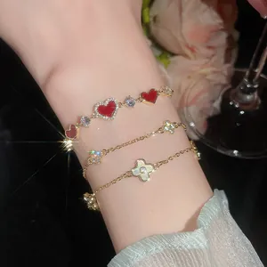 Detailansicht von 14k vergoldeten Armbändern mit Herz-Zirkonia und Perlmutt-Blumen
