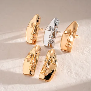 Orecchini a maschera astratta in metallo oro e argento con dettagli artistici unici.