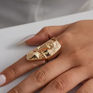 Dettaglio di un anello a forma di maschera dorata metallica in stile audace su una mano