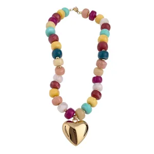 Collana di perle in acrilico colorato con ciondolo a cuore in oro lucido su sfondo bianco