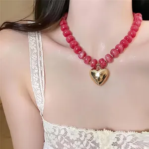 Primo piano della collana di perle acriliche venate con ciondolo a cuore dorato