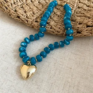 Primo piano di una collana di perle acriliche blu marmorizzate con un cuore d'oro lucido