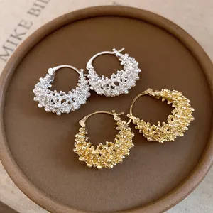 Close-up of French hollow basket hoop earrings in gold and silver textured finish