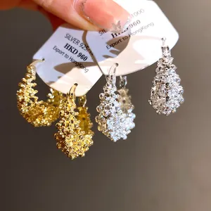 Close-up detail of French openwork flower basket earrings in gold and silver finishes