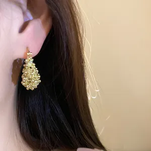 Close-up of a gold French style hollow basket earring worn on ear showing fine detail.